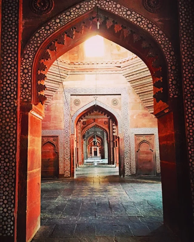 A corridor of repeating red and white patterned arches in India.